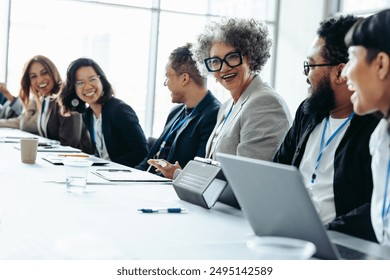 Group of diverse colleagues laughing and engaging during a corporate meeting in a bright, modern office environment - Powered by Shutterstock