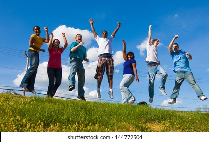 A Group Of Diverse College Students/friends Jumping In The Air Outside On A Hill