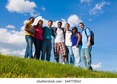 A Group Of Diverse College Students/friends Outside On A Hill With A Sky Background