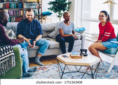 Group of diverse content people in casual clothing sitting in cozy living room and chatting while relaxing together and looking at each other - Powered by Shutterstock