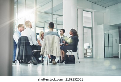 Group Of Diverse Coworkers Talking Together While Sitting In A Circle In An Office. Employees Having A Team Business Meeting Discussion For Counseling Or Support Group At A Corporate Workplace.