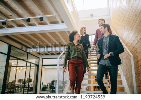 Group of diverse coworkers walking down the stairs in an office