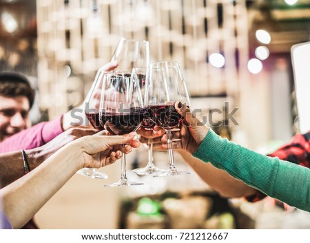 Group of diverse culture friends cheering with red wine in trendy winery bar - Happy people drinking and having fun pub restaurant after work - Party and nightlife concept - Focus on close up hands