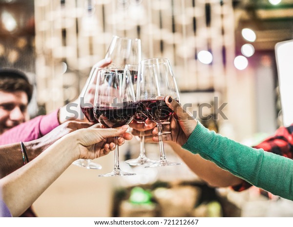 Group of diverse culture friends cheering with red\
wine in trendy winery bar - Happy people drinking and having fun\
pub restaurant after work - Party and nightlife concept - Focus on\
close up hands