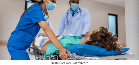 Group of diverse doctors moving seriously injured patient in hospital. Attractive professional medic surgeon people in a hurry move emergency patient lying on a stretcher into operating theater room. - Powered by Shutterstock