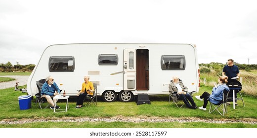 Group of diverse elderly people enjoy caravan camping trip in nature. Diverse elderly friends sit and relax outdoors, caravan camping. Elderly friends group camping outdoor, enjoy relax nature trip - Powered by Shutterstock