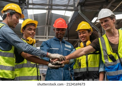 Group of diverse Engineer and workers wear safety vests with helmets join hands to collaborate with team working in factory