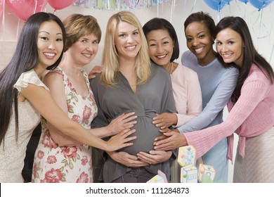 Group of diverse female friends touching tummy of pregnant woman