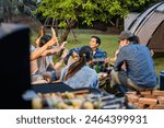 Group of diverse friend having outdoors camping party together in tent. Attractive young man and woman traveler dancing with music, enjoy hangout during holiday vacation trip in nature wood forest.