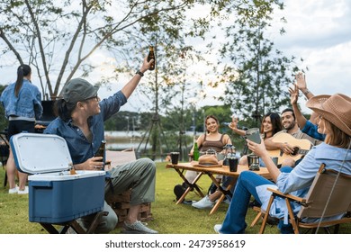 Group of diverse friend having outdoors camping party together in tent. Attractive young man and woman traveler drinking alcohol beer, enjoy hanging out during holiday vacation trip in wood forest. - Powered by Shutterstock