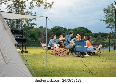 Group of diverse friend having outdoors camping party together in tent. Attractive young man and woman traveler drinking alcohol beer, enjoy hanging out during holiday vacation trip in wood forest. - Powered by Shutterstock