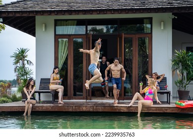 Group of diverse friend jumping into the pool, having a party together. Attractive young man and woman hanging out, celebrating summer vacation enjoying sunny day on travel holiday at a private villa. - Powered by Shutterstock