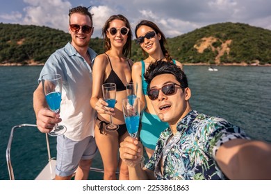 Group of diverse friend taking photo and drink champagne while yachting. Attractive young men and women hanging out, celebrating holiday vacation trip while catamaran boat sailing during summer sunset - Powered by Shutterstock