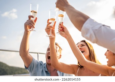 Group of diverse friends drink champagne while having a party in yacht. Attractive young men and women hanging out, celebrating holiday vacation trip while catamaran boat sailing during summer sunset. - Powered by Shutterstock