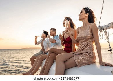 Group of diverse friends drink champagne while having a party in yacht. Attractive young men and women hanging out, celebrating holiday vacation trip while catamaran boat sailing during summer sunset. - Powered by Shutterstock