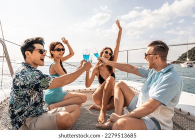 Group of diverse friends drink champagne while having a party in yacht. Attractive young men and women hanging out, celebrating holiday vacation trip while catamaran boat sailing during summer sunset. - Powered by Shutterstock