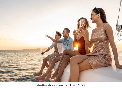 Group of diverse friends drink champagne while having a party in yacht. Attractive young men and women hanging out, celebrating holiday vacation trip while catamaran boat sailing during summer sunset. - Powered by Shutterstock