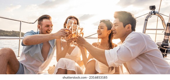 Group of diverse friends drink champagne while having a party in yacht. Attractive young men and women hanging out, celebrating holiday vacation trip while catamaran boat sailing during summer sunset. - Shutterstock ID 2316853185