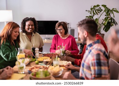 Group of diverse friends are enjoying each other's company and having a good time while eating and drinking at a dinner party - Powered by Shutterstock