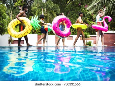 Group of diverse friends enjoying summer time by the pool with inflatable tubes - Powered by Shutterstock