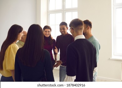 Group Of Diverse Friends Gather Together In Club Meeting. Smiling Convincing Friendly Coach Talking To Team Of Multiethnic People, Suggesting Interesting Idea, Teaching To Play Funny Ice Breaker Game