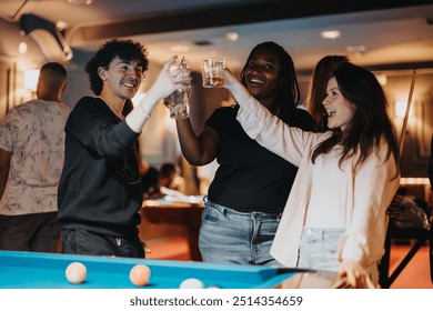 Group of diverse friends having fun and toasting drinks while playing billiard at a cozy bar during a night out. - Powered by Shutterstock