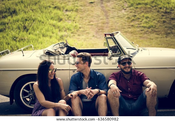 Group of Diverse Friends Sitting on Road by the\
Car Together