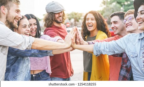 Group of diverse friends stacking hands outdoor - Happy young people having fun joining and celebrating together - Millennials, friendship, empowering, partnership and youth lifestyle concept 