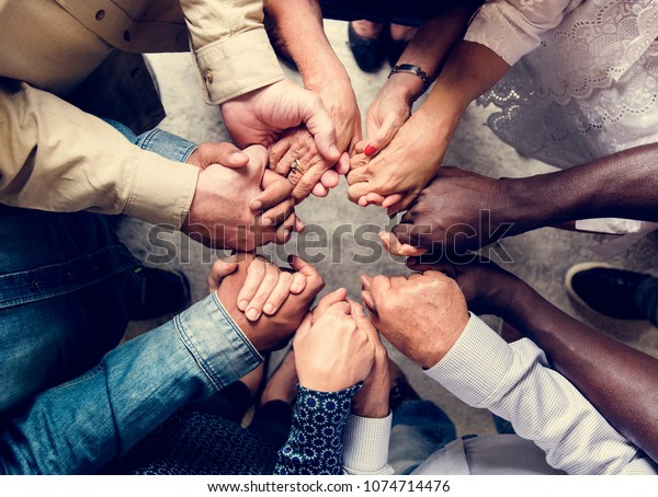 Group of diverse hands holding each other\
support together teamwork aerial\
view