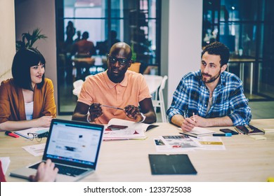 Group of diverse hipster student sitting at desktop with laptop computer having brainstorming meeting in coworking space.Smart casual dressed young people teamworking on common project in office - Shutterstock ID 1233725038