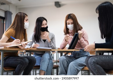 Group Of Diverse International Students Wearing Protective  Masks And Talking, Discussing Project, Sitting At Desk In The Classroom At The University