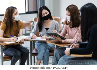 Group of diverse international students wearing protective  masks and talking, discussing the project, sitting at the desk in the classroom at the university