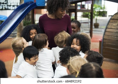 Group of diverse kindergarten students with teacher at playground