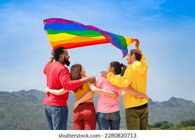 group of diverse lgbtq friends wearing colorful clothes, standing side by side, smiling and holding lgbt flags waving in the air, concept of lgbt community equality movement, lgbt happy pride month