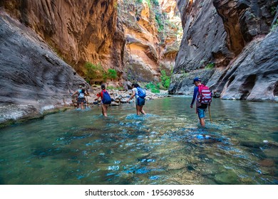 Group of diverse people hiking through a river at Zion National Park. Exploring the beauty of the Narrows and the beautiful canyons of the narrows