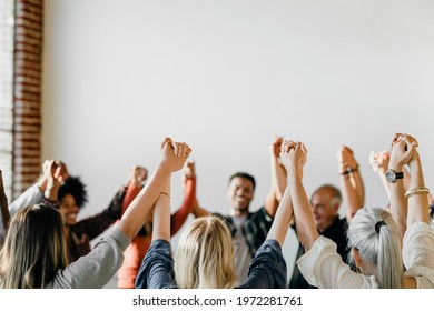 Group of diverse people holding hands up in the air - Powered by Shutterstock