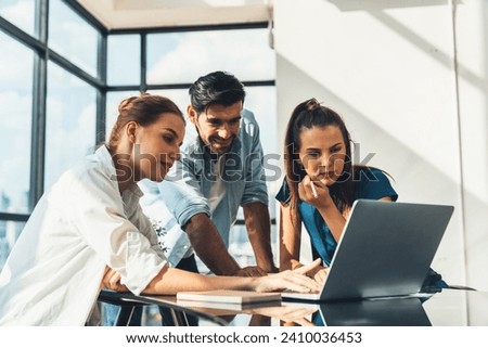 Group of diverse profession business people pointing at laptop displayed idea. Portrait of business team show marketing strategy present by laptop with statistic document scatter on table. Tracery.