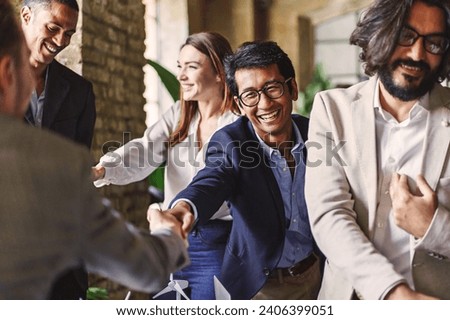 Group of diverse professionals celebrating with a handshake at a corporate event, embodying teamwork and achievement.