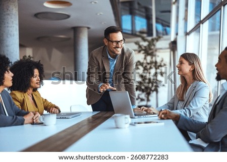 A group of diverse professionals engaging in a collaborative discussion at a workplace. The interaction conveys teamwork, productivity, and professional enthusiasm in a modern corporate environment.