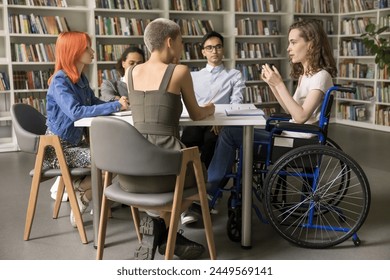 Group of diverse schoolmates listening team leader, girl with physical disability make speech seated in wheelchair, share opinion or insight, offers problem solution, working together on joint task - Powered by Shutterstock