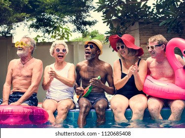 Group Of Diverse Senior Adults Sitting By The Pool Enjoying Summer Together