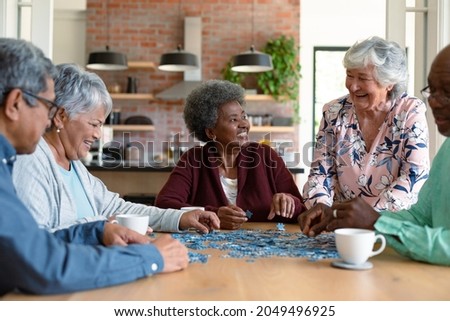 Group of diverse senior male and female friends doing puzzles at home. socialising with friends at home.