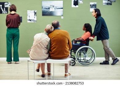 Group Of Diverse Senior And Young People Spending Free Time In Modern Art Gallery Looking At Abstract Photos And Relaxing