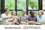 Group of diverse seniors enjoying a meal, laughing and toasting with wine. Happy gathering of elderly friends sharing food and joy around a table. Senior people toasting with wine during lunch.