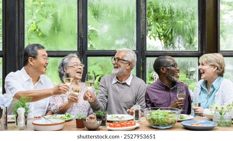 Group of diverse seniors enjoying a meal, laughing and toasting with wine. Happy gathering of elderly friends sharing food and joy around a table. Senior people toasting with wine during lunch. - Powered by Shutterstock