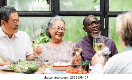 Group of diverse seniors enjoying a meal, smiling and toasting with wine. Happy seniors, diverse group, enjoying a healthy meal together, sharing joy and laughter. Happy and healthy senior lifestyle.  - Powered by Shutterstock