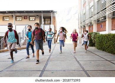 Group Of Diverse Students Wearing Face Masks Running At Elementary School. Education Back To School Health Safety During Covid19 Coronavirus Pandemic.