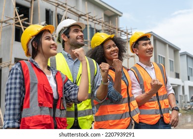 Group of diverse teamwork civil engineers and architect wear safety vests with helmets standing raising fist celebrating work success at housing estate construction site - Powered by Shutterstock