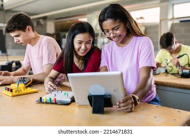 Group of diverse teenage students learning together to build electronic circuits at high school - Asian and african american female classmate working at technology class - Powered by Shutterstock