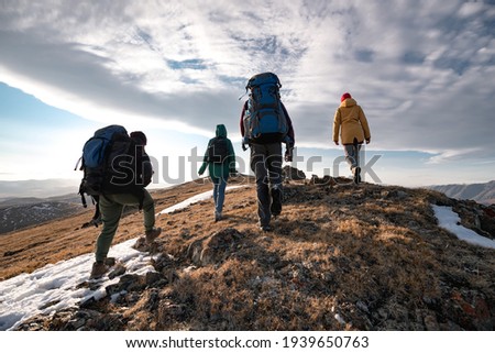 Group of diverse tourists or hikers walks on mountain top
